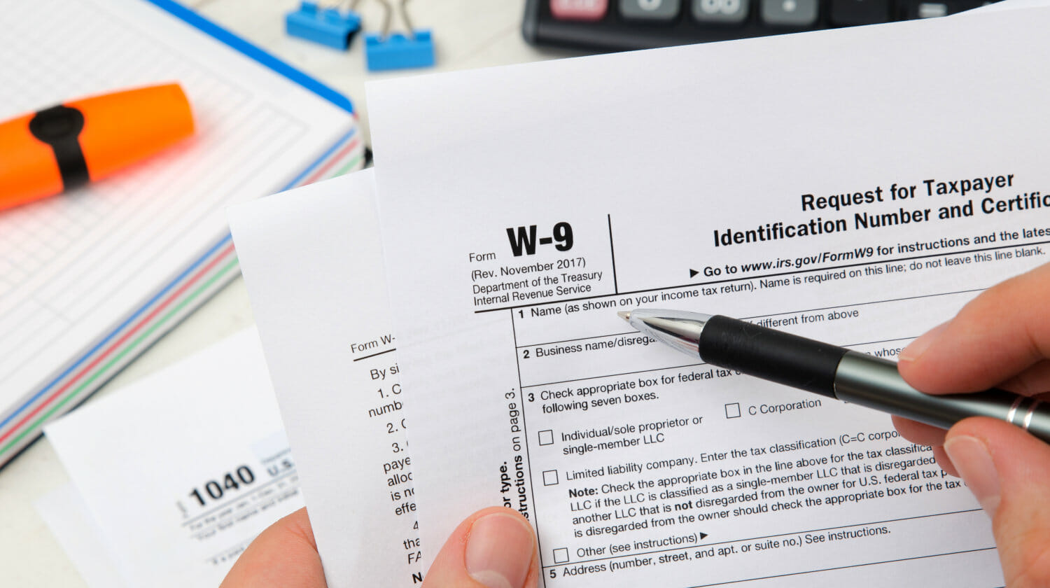 Featured | Man holding US tax form W-9 | Basics Of The IRS W9 Form