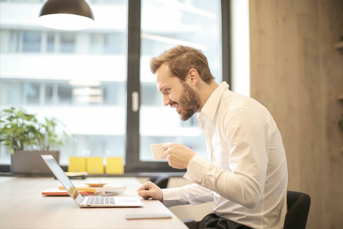 man holding teacup infront of laptop | Tax Write Offs | Your Guide To All Itemized Deductions
