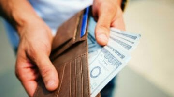 Feature | man holding brown leather bi fold wallet with money | How Much Should I Save From My Income Every Month | How much should I save for retirement