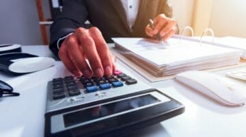 Feature | businessperson hand calculating bills | IRS Penalty Calculator: Breaking Down Your IRS Late Fees | irs penalty and interest calculator