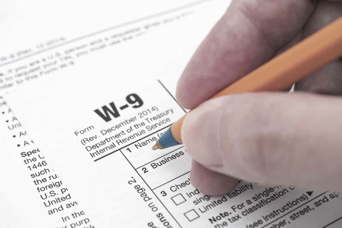 person hand with ballpoint pen filling out form W-9 | What Is A Tax Lien? | FAQs | federal lien