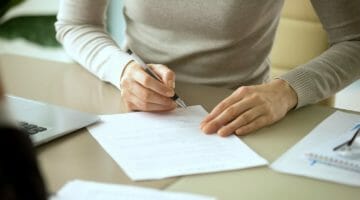 Feature | woman signing document | Tax Debt Forgiveness Frequently Asked Questions | tax debt forgiveness