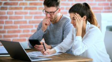 Feature | worried young couple calculating bills home | How To Get Your Underpayment Penalty Waived | tax underpayment penalty