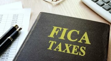 FICA taxes and calculator on a table | A Complete Guide To FICA Taxes | fica tax | what is fica tax | Featured